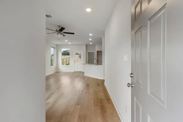 a view of a hallway with wooden floor and a bathroom