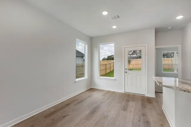 a view of an empty room with a window and wooden floor
