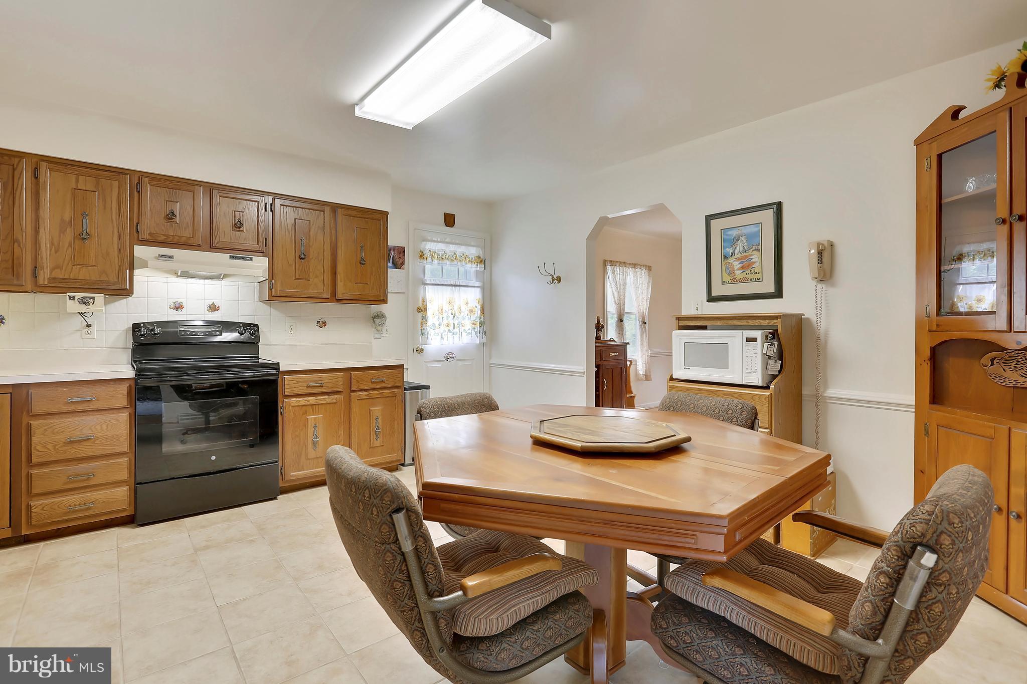 464 Friendship Road Friendship, MD 20758 - Photo 21 of 29 a kitchen with stainless steel appliances kitchen island granite countertop a table chairs stove and white cabinets