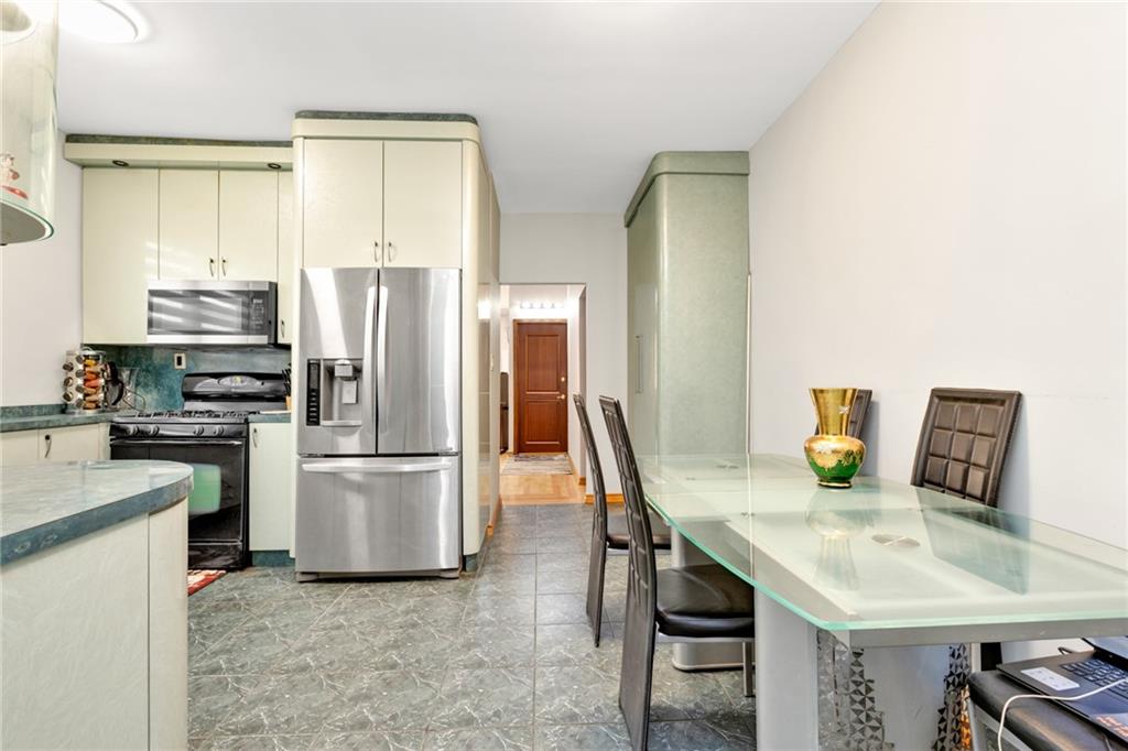 449 Ave Y Brooklyn, NY 11223 - Photo 7 of 25 a kitchen with stainless steel appliances a refrigerator a stove a kitchen island a stove a table and chairs
