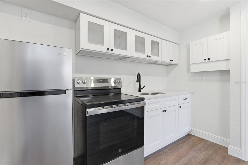 113 145th Avenue, Unit 4 Madeira Beach, FL 33708 - Photo 5 of 28 a kitchen with stainless steel appliances white cabinets and wooden floor