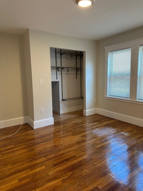 78 Harriet Street, Unit 1 Boston, MA 02135 - Photo 11 of 22 an empty room with wooden floor cabinet and windows