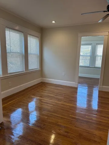 a view of empty room with wooden floor and fan
