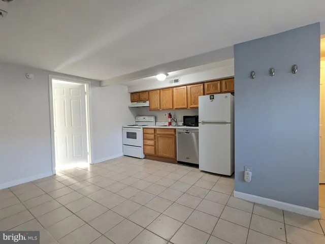 a kitchen with a refrigerator a stove top oven and cabinets