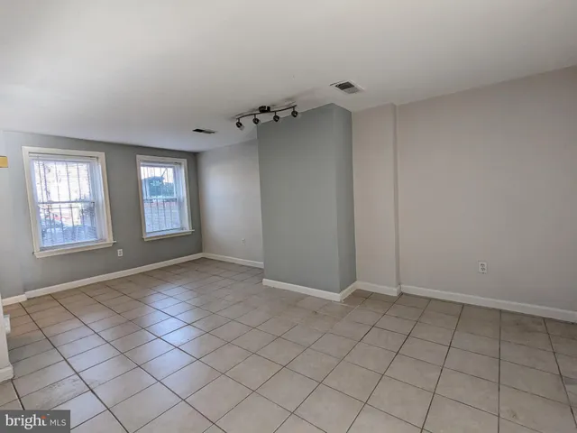 a view of an empty room with window and chandelier fan