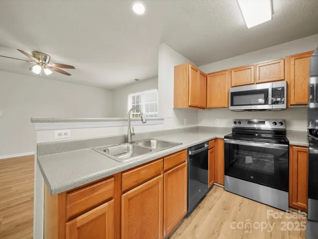 a kitchen with stainless steel appliances granite countertop a sink a stove a microwave and wooden cabinets