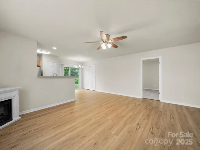 a view of an empty room and chandelier fan