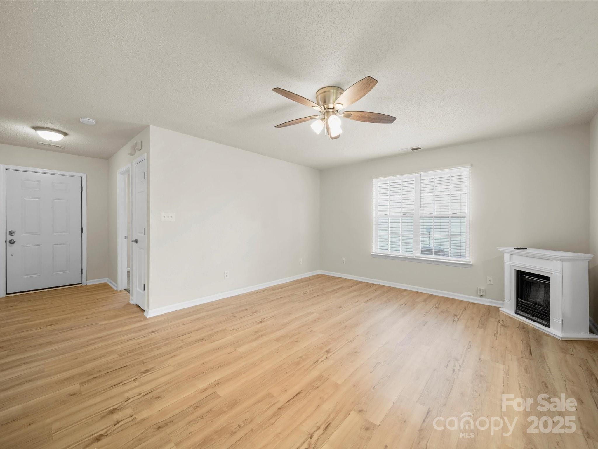 6420 Sunman Road Charlotte, NC 28216 - Photo 7 of 43 an empty room with wooden floor fireplace and windows