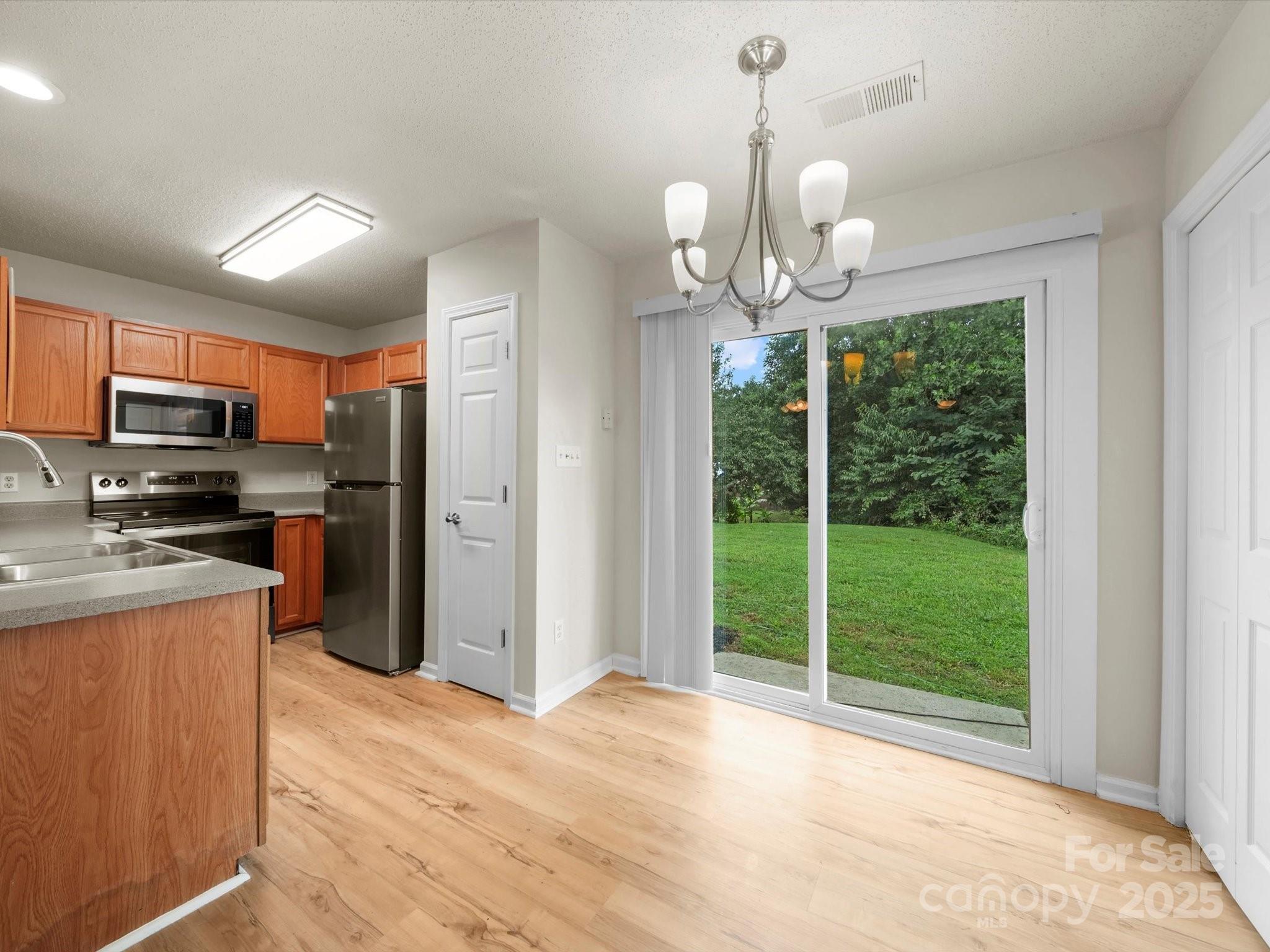 6420 Sunman Road Charlotte, NC 28216 - Photo 8 of 43 a view of a kitchen with stainless steel appliances granite countertop a refrigerator a stove top oven a sink with wooden floor and cabinets