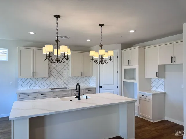 a view of a kitchen with a sink a center island and cabinets