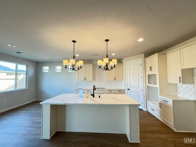 a view of living room kitchen island stainless steel appliances and wooden floor