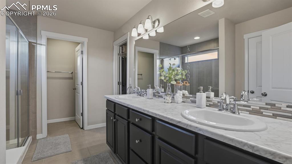 7872 Callendale Drive Colorado Springs, CO 80908 - Photo 25 of 50 Upper level Primary Bathroom with dual sink vanity, enclosed tiled shower with built-in seat, and walk in closet.