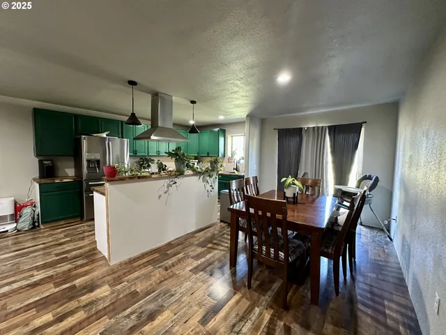 a kitchen with stainless steel appliances kitchen island granite countertop a table chairs sink and cabinets