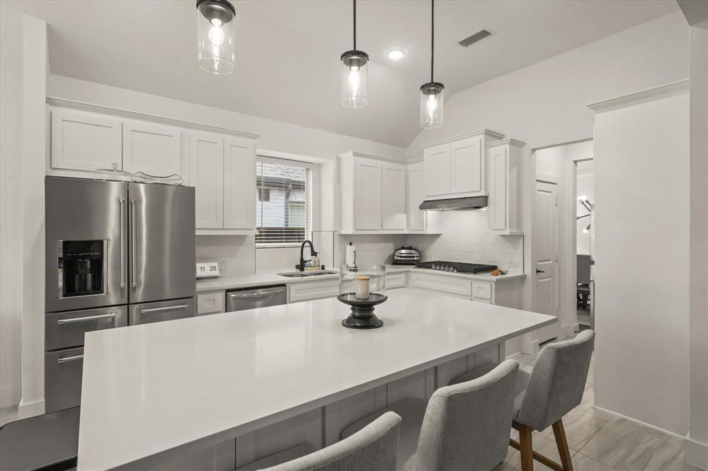 1714 Highwood Road Forney, TX 75126 - Photo 11 of 30 Bright kitchen featuring white shaker cabinetry, stainless steel appliances, a center island with countertop seating, and pendant lighting