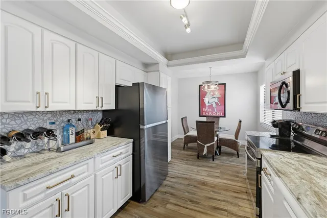 a kitchen with stainless steel appliances granite countertop a refrigerator a sink dishwasher a dining table and chairs with wooden floor