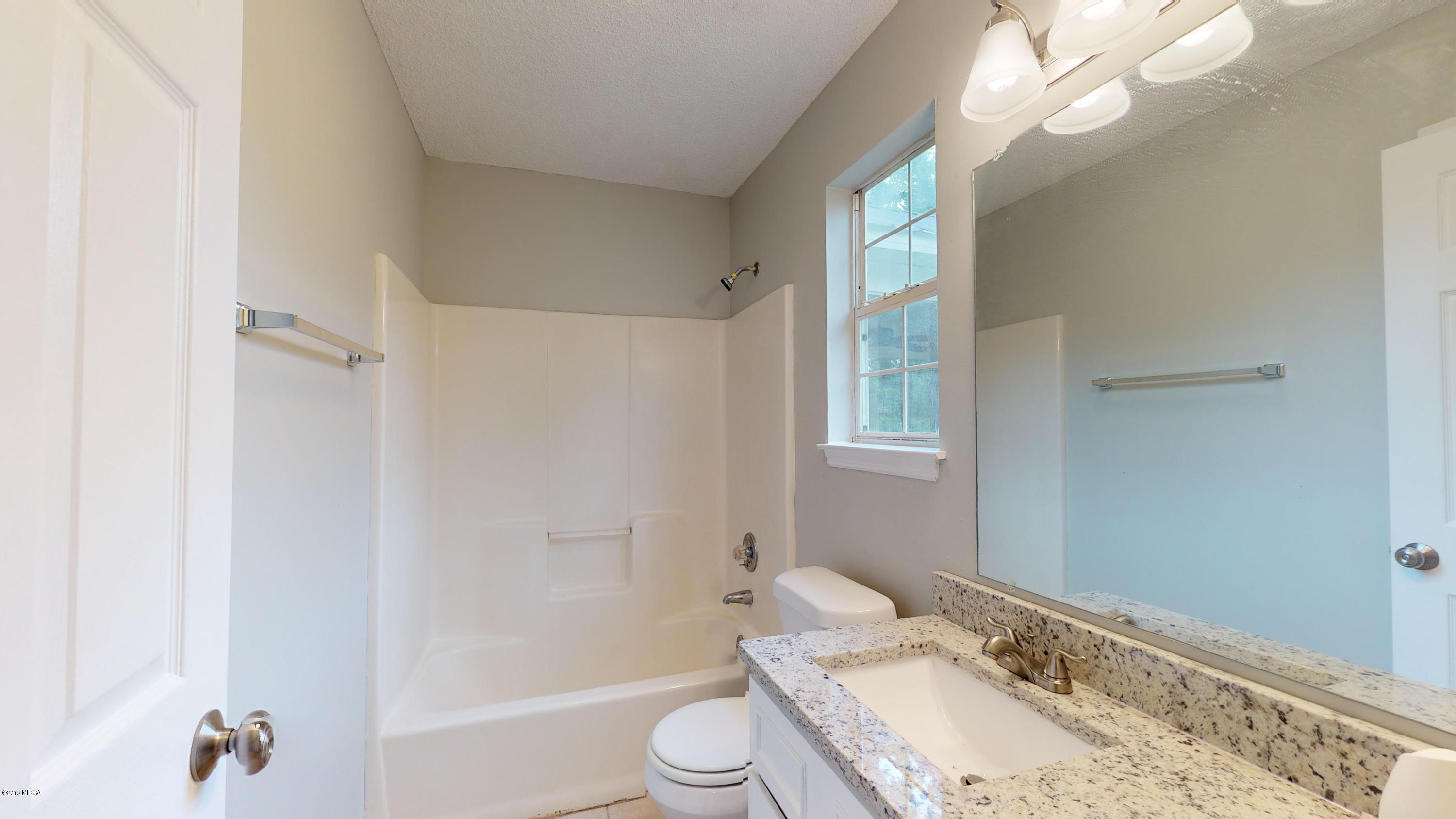 639 Lassiter Road Forsyth, GA 31029 - Photo 4 of 25 a bathroom with a granite countertop sink toilet a large mirror and shower