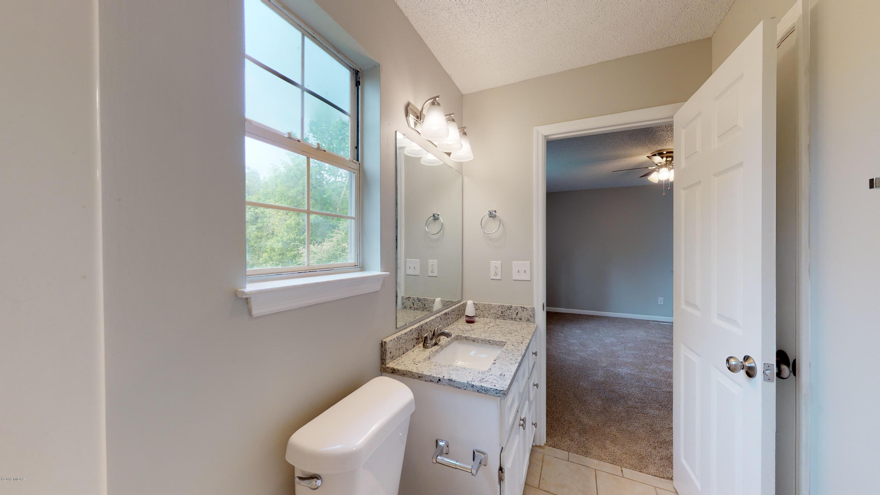 639 Lassiter Road Forsyth, GA 31029 - Photo 5 of 25 a bathroom with a granite countertop sink toilet and shower