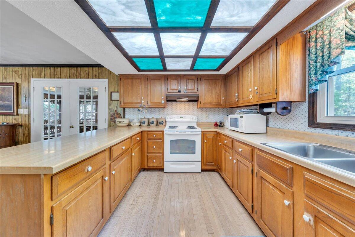 3878 Harborwood Road Salem, VA 24153 - Photo 21 of 60 a kitchen with stainless steel appliances granite countertop a stove a sink dishwasher and white cabinets with wooden floor