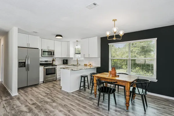 a kitchen with a table chairs refrigerator and microwave