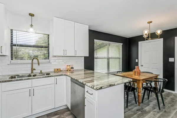 a kitchen with a stove a sink a refrigerator and a dining table with wooden floor