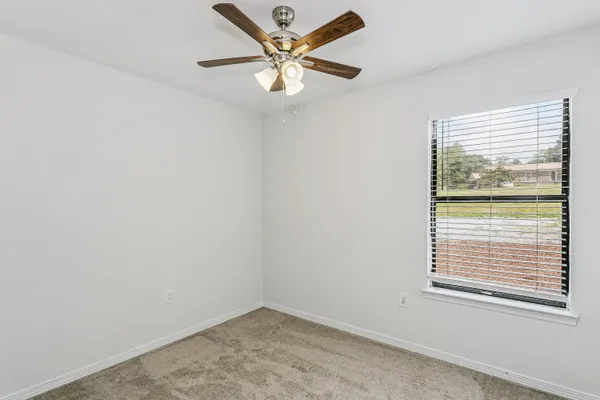 an empty room with a window and a fan