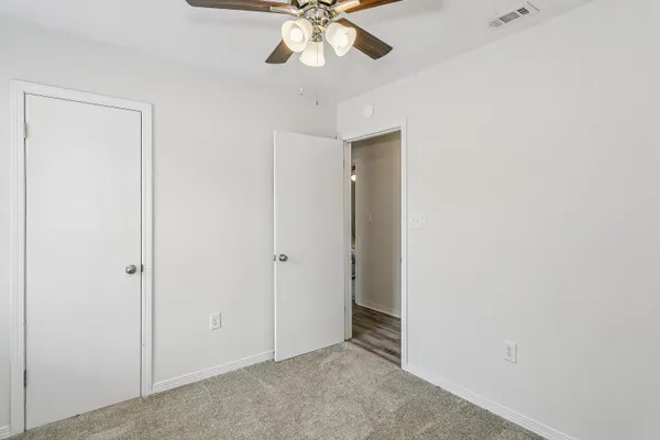 a view of an empty room and chandelier fan