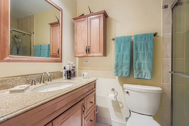 a bathroom with a granite countertop toilet sink and mirror