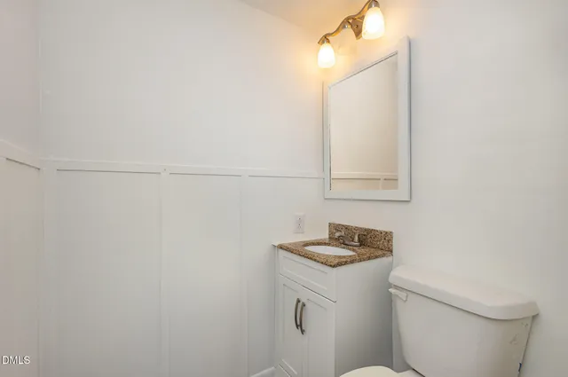 a bathroom with a granite countertop toilet and sink