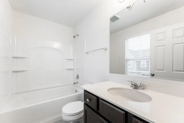 a bathroom with a granite countertop sink a toilet a shower and a mirror