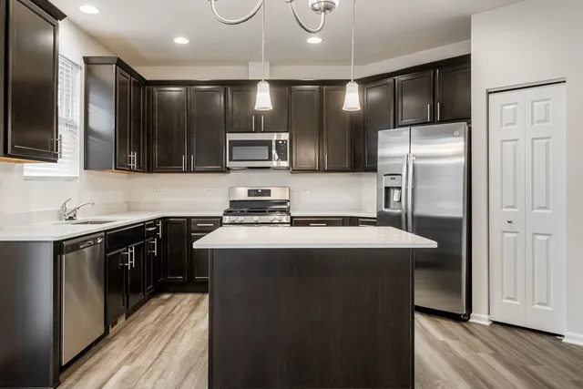 a kitchen with kitchen island a counter space a sink appliances and cabinets