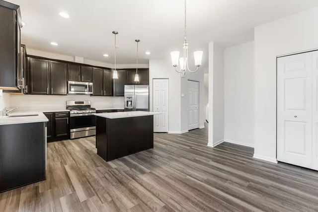 a kitchen with stainless steel appliances kitchen island granite countertop a refrigerator and a stove top oven