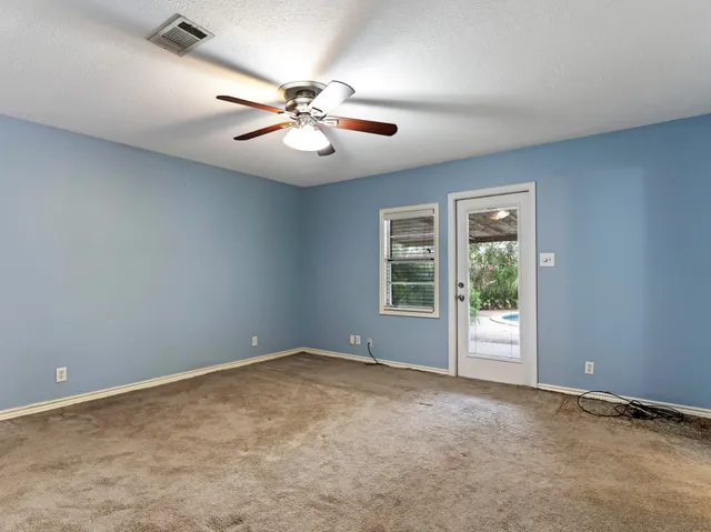 an empty room with windows and fan