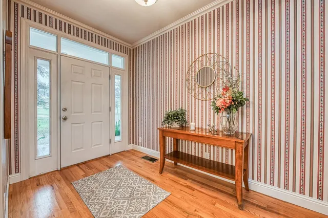 a kitchen with stainless steel appliances granite countertop wooden cabinets a refrigerator a sink a stove and island with wooden floor