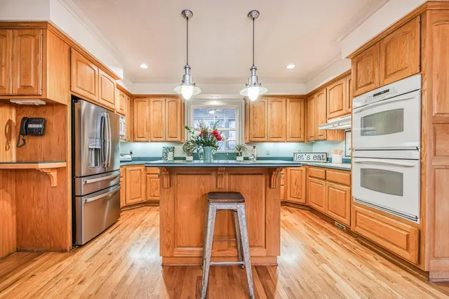 a kitchen with stainless steel appliances granite countertop a refrigerator a stove and a wooden floors