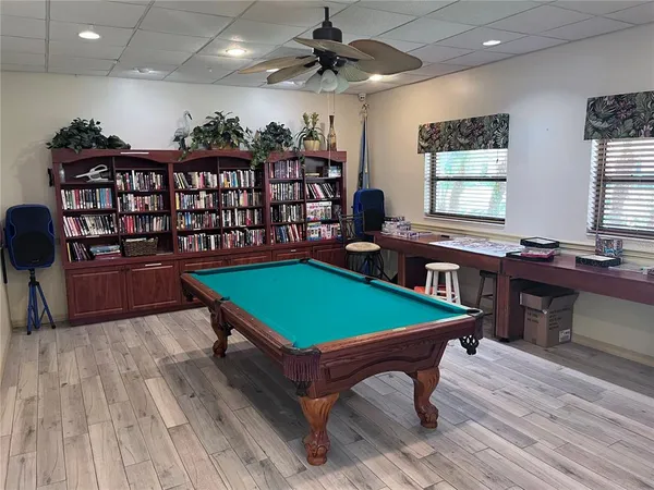 a room with wooden floor pool table and windows
