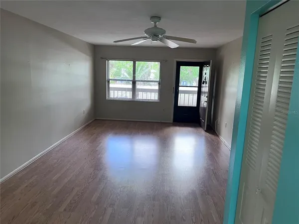 an empty room with wooden floor and windows