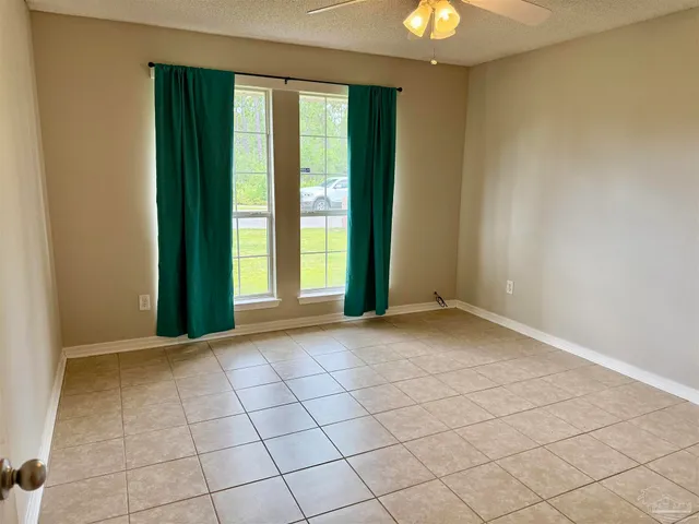 a view of an empty room and chandelier fan