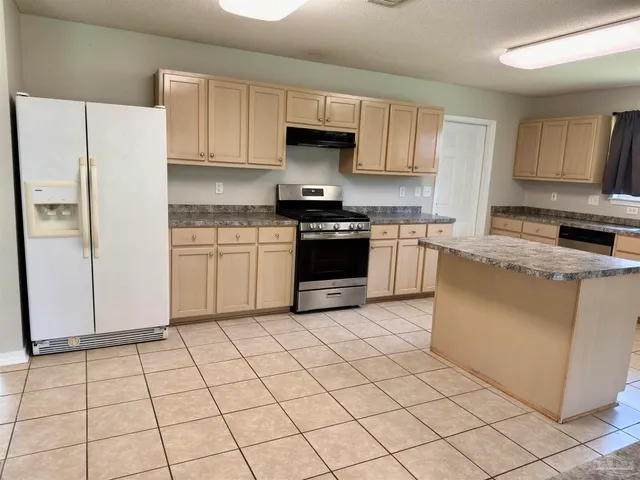 a kitchen with granite countertop a stove a sink and a refrigerator