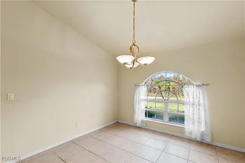 a view of an empty room with a chandelier fan and a window