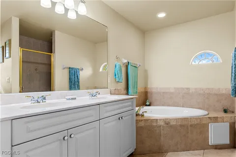 a bathroom with a double vanity sink mirror and bathtub