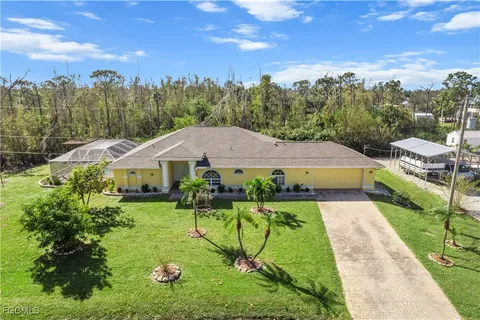 an aerial view of a house with yard and trees in the background
