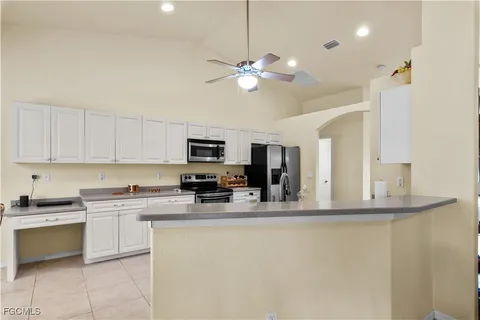 a kitchen with kitchen island granite countertop a sink a counter top space appliances and cabinets
