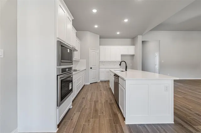 a kitchen with a sink a counter top space stainless steel appliances and cabinets
