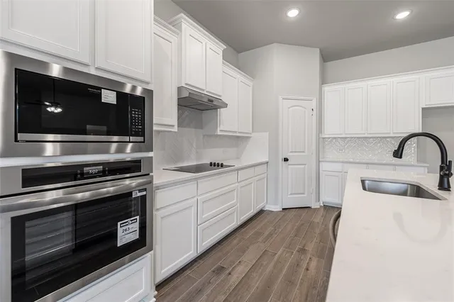 a kitchen with stainless steel appliances a stove microwave and sink