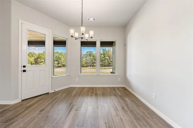 an empty room with wooden floor exposed radiator and windows