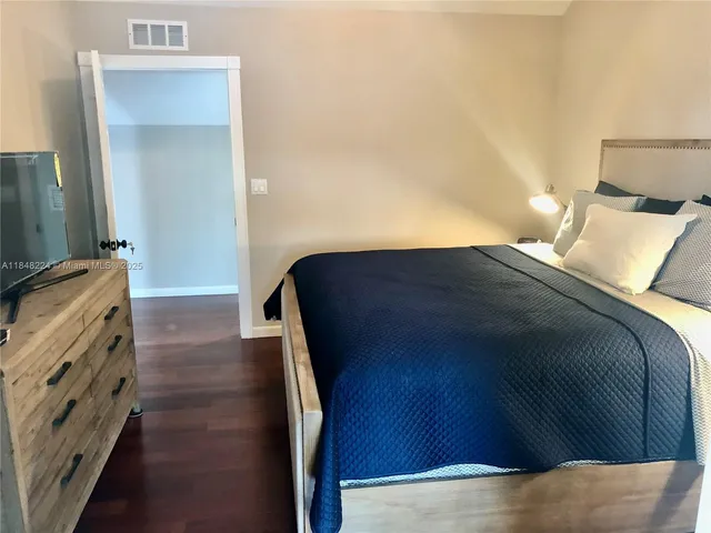 a bedroom with a bed and a flat tv screen on dresser