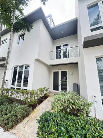 a view of a white house with large windows and flower plants