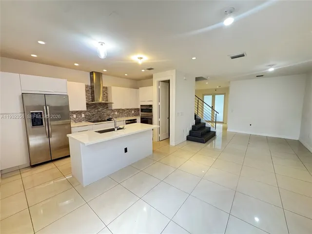 a kitchen with kitchen island granite countertop a sink and cabinets