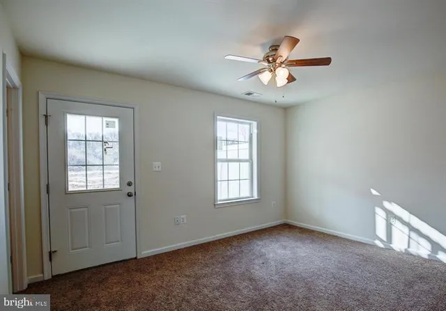 an empty room with windows and fan