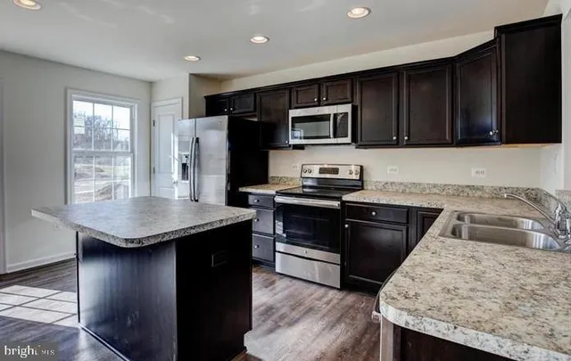 a kitchen with granite countertop stainless steel appliances a stove sink microwave and refrigerator